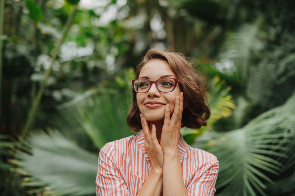 Woman standing in botanical garden, in the middle of lush green foliage.