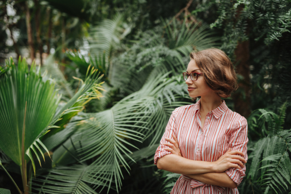 Woman standing in botanical garden, in the middle of lush green foliage.