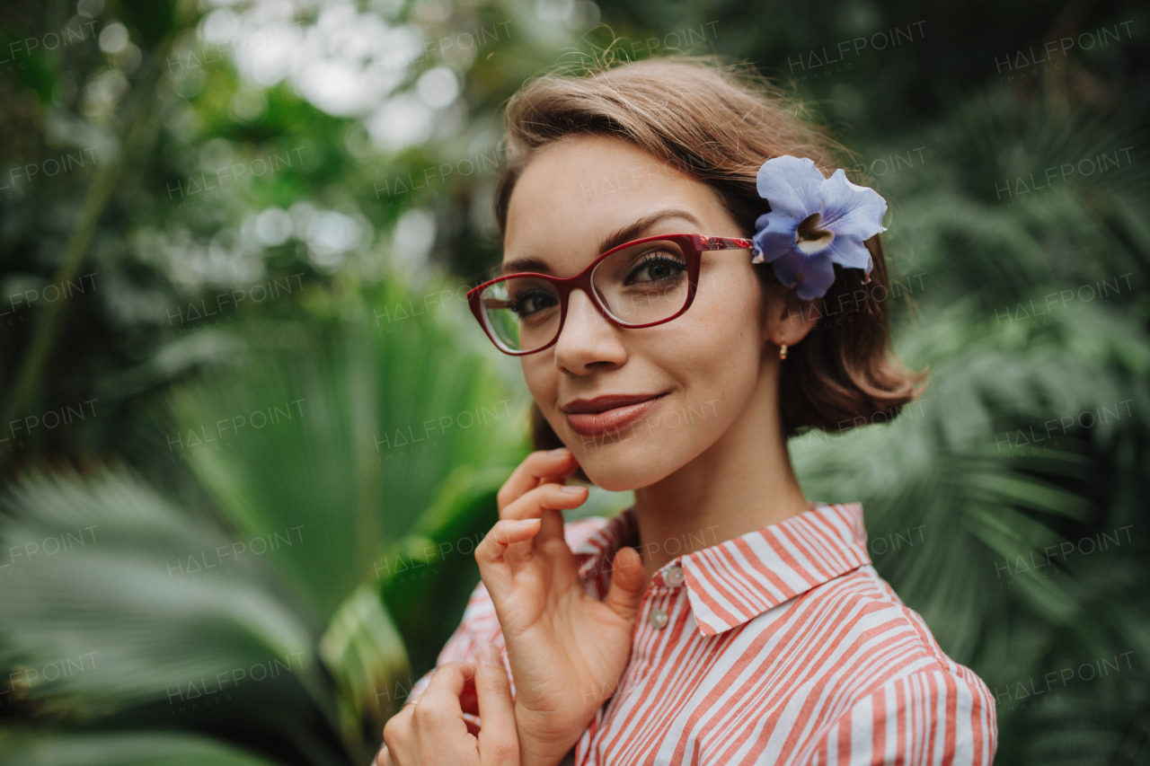 Woman standing in botanical garden, in the middle of lush green foliage.