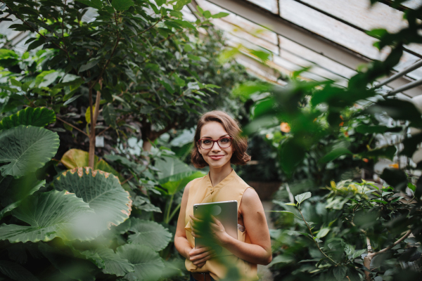 Woman standing in botanical garden, in the middle of lush green foliage.