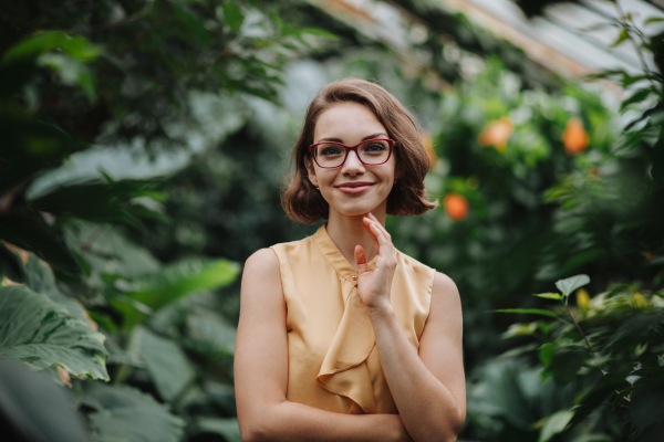 Woman standing in botanical garden, in the middle of lush green foliage.