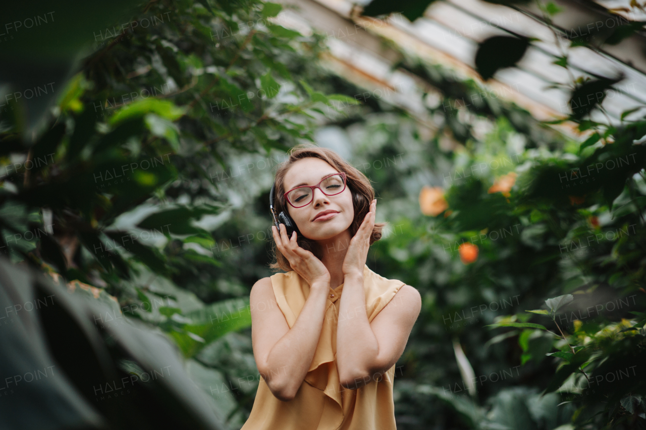 Woman standing in botanical garden, in the middle of lush green foliage.