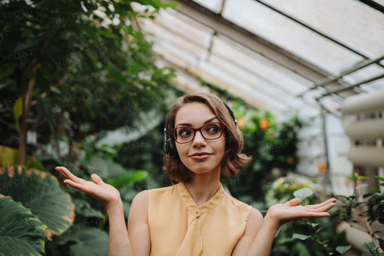 Woman standing in botanical garden, in the middle of lush green foliage.