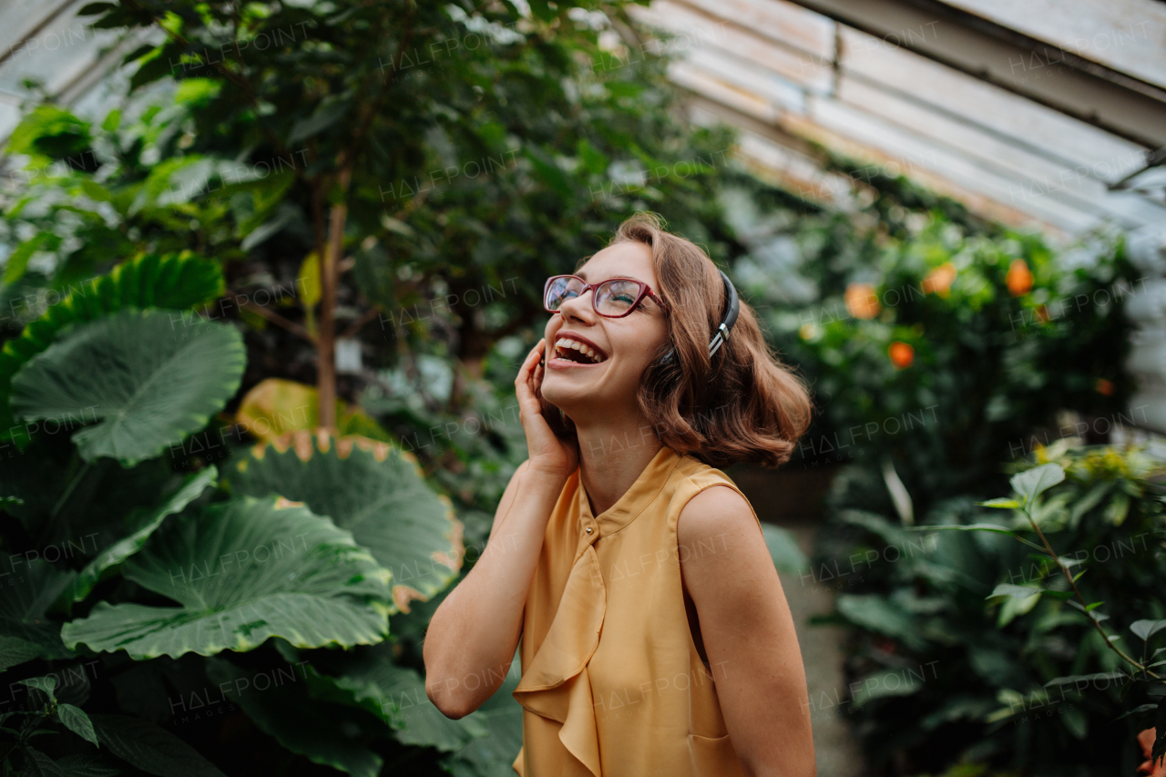 Woman standing in botanical garden, in the middle of lush green foliage.