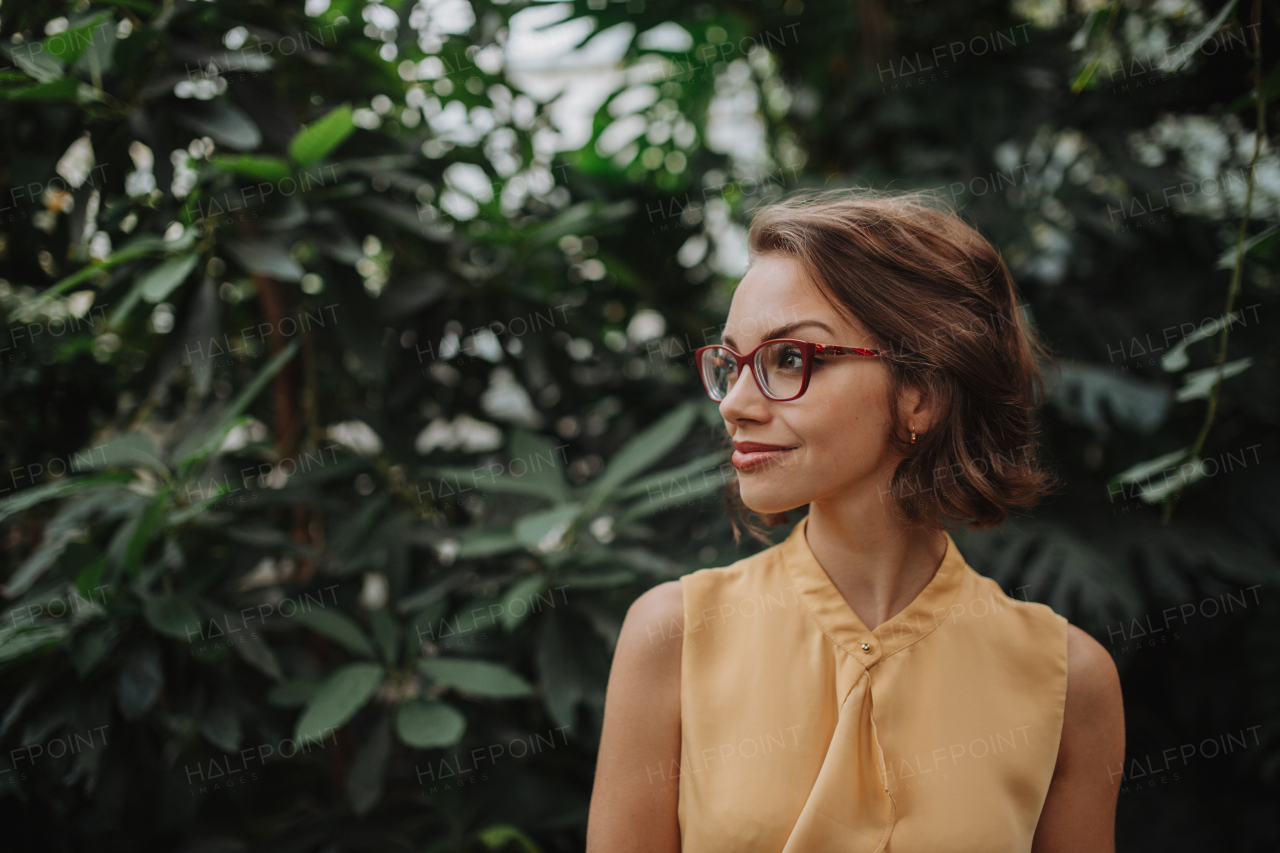 Woman standing in botanical garden, in the middle of lush green foliage.