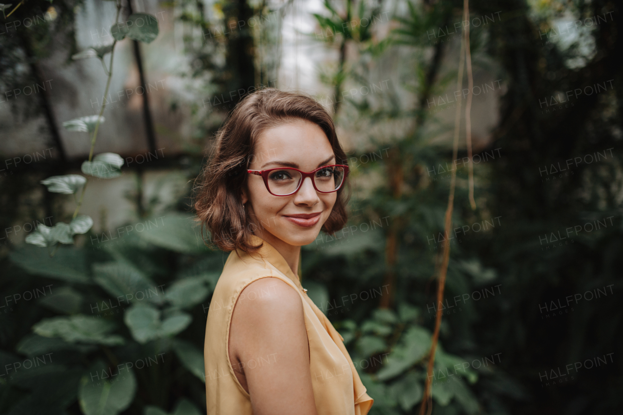 Woman standing in botanical garden, in the middle of lush green foliage.