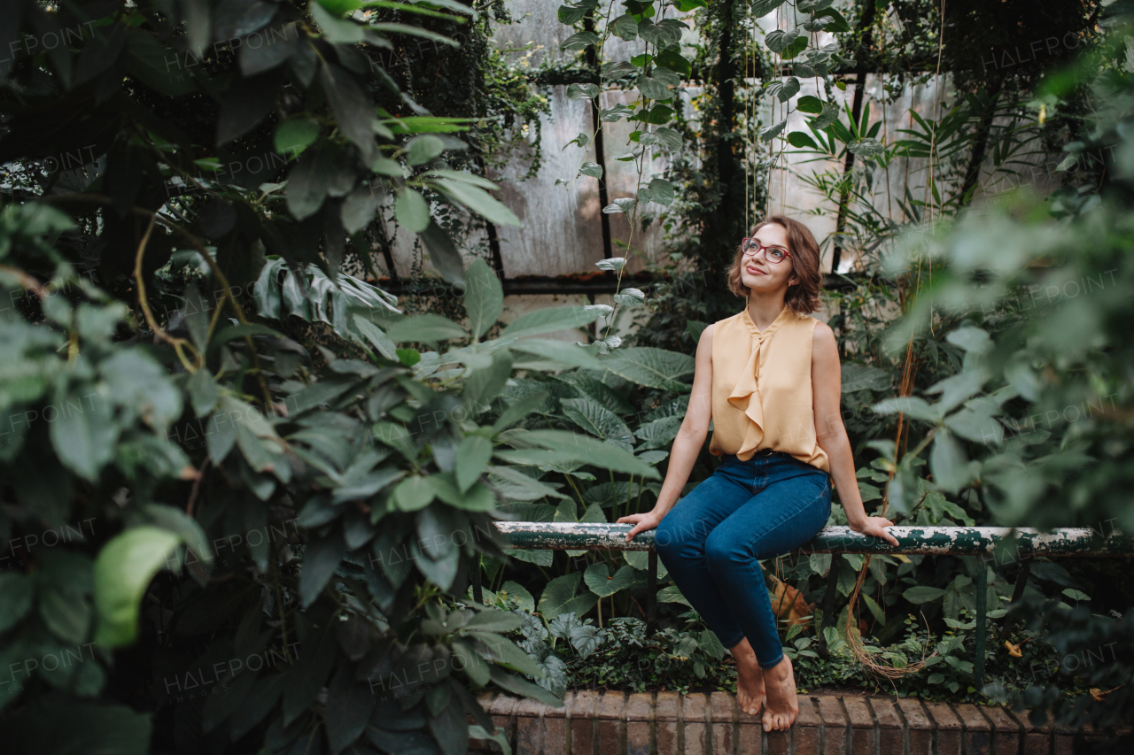 Woman sitting in botanical garden, in the middle of lush green foliage.