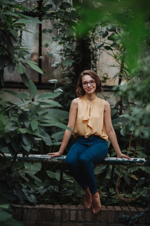 Woman sitting in botanical garden, in the middle of lush green foliage.