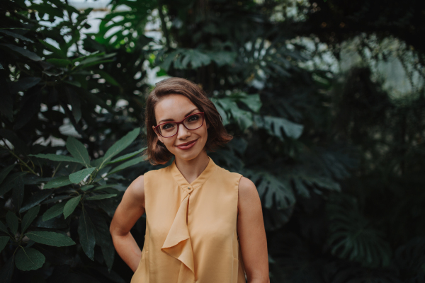 Woman standing in botanical garden, in the middle of lush green foliage.