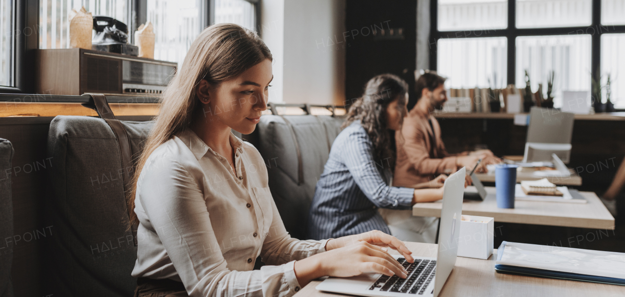 Group of freelancers and remote businesspeople working in shared work area. Concept of coworking, common workspaces for business, startups. Working remotely from coffee shop.