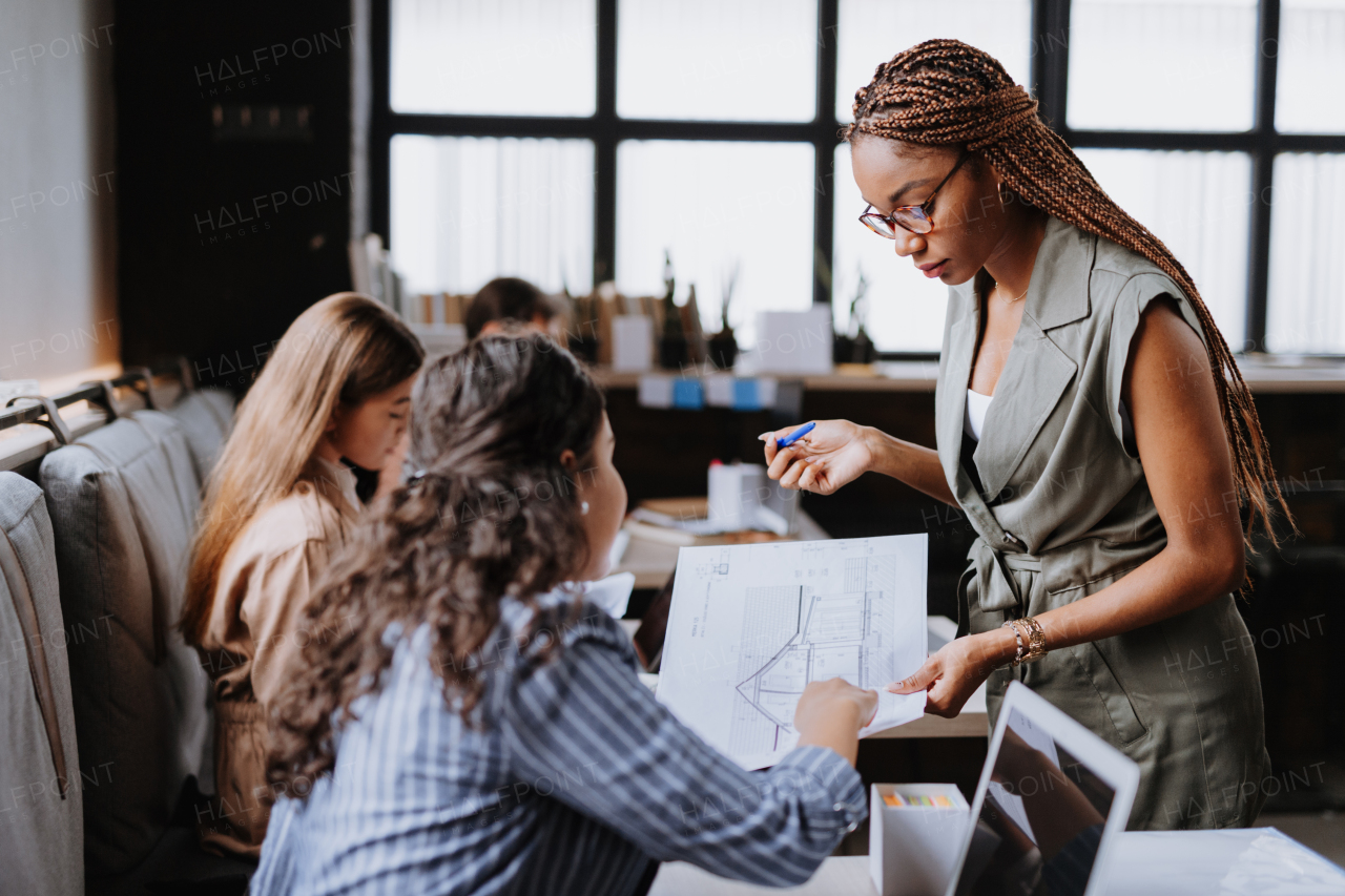 People in coworking space sharing ideas, collaboring, talking about project. Group of freelancers and remote businesspeople working in shared work area. Concept of coworking as modern working arragement. Working remotely from coffee shop.