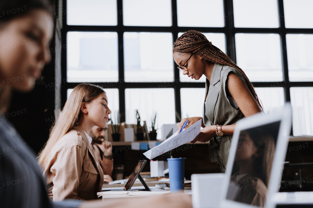 People in coworking space sharing ideas, collaboring, talking about project. Group of freelancers and remote businesspeople working in shared work area. Concept of coworking as modern working arragement. Working remotely from coffee shop.