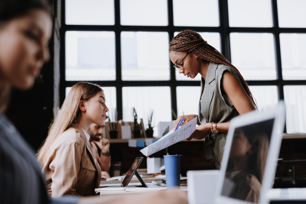 People in coworking space sharing ideas, collaboring, talking about project. Group of freelancers and remote businesspeople working in shared work area. Concept of coworking as modern working arragement. Working remotely from coffee shop.