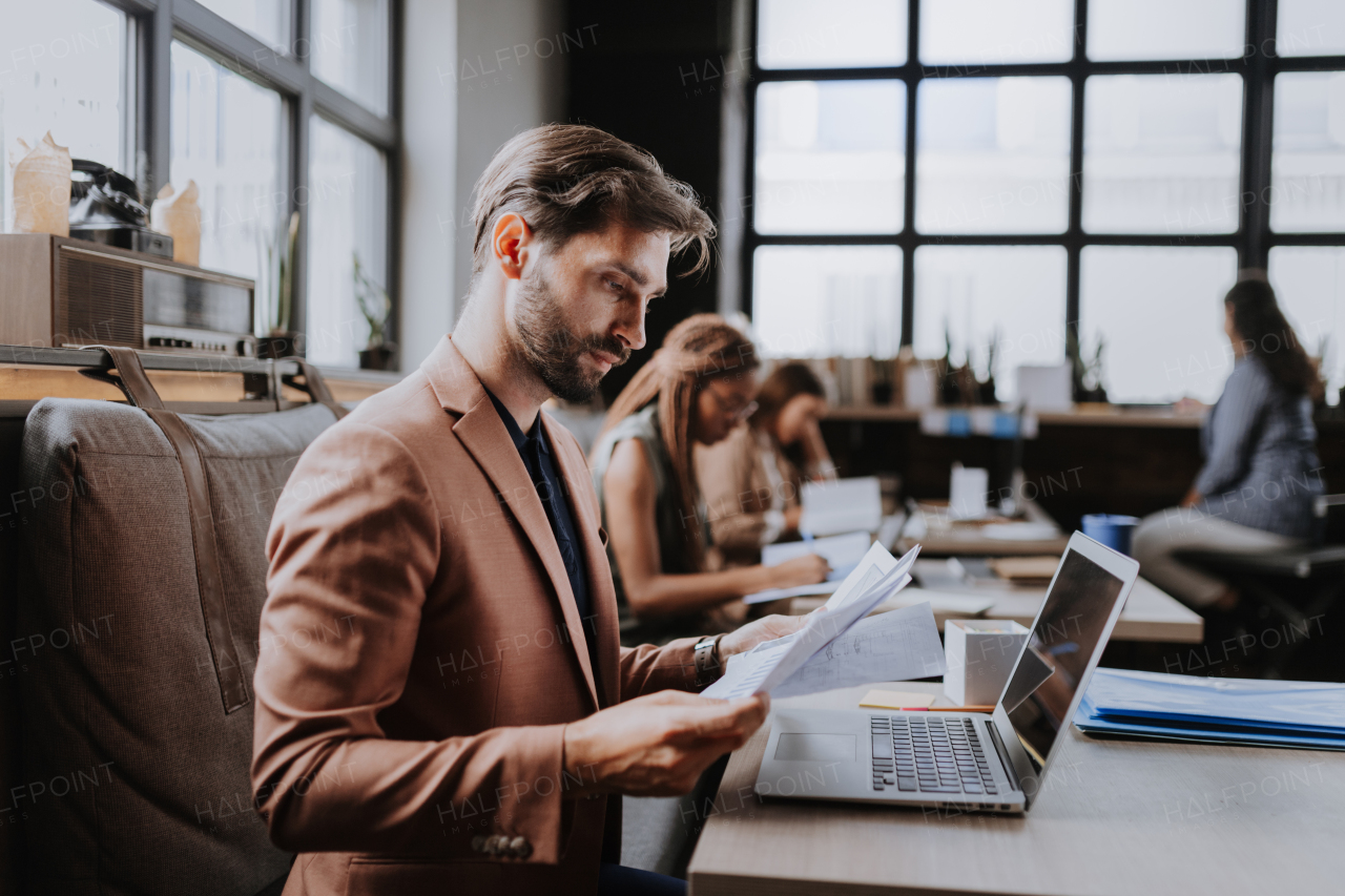 Businessman working on laptop in modern office or coworking area. Working remotely from the coffee shop. Concept of coworking, common workspaces for business, startups.