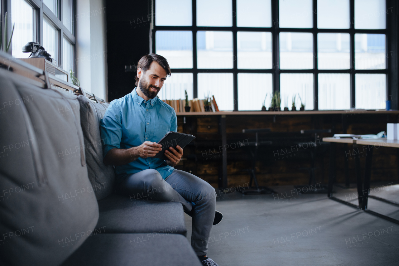 Handsome businessman preparing for meeting, working on presentation on tablet, sitting in modern office. Working remotely from coffee shop.