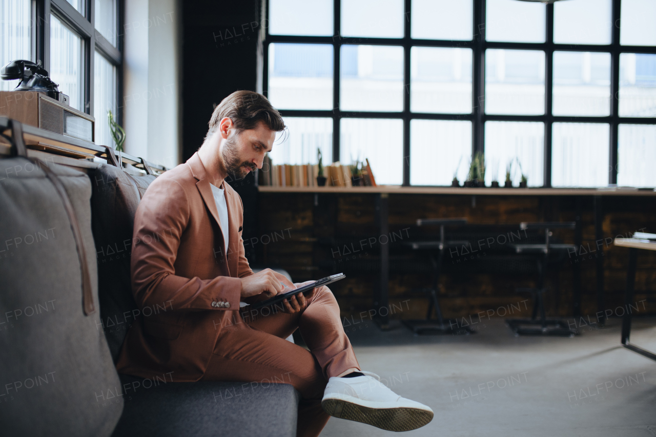 Handsome businessman preparing for meeting, working on presentation on tablet, sitting in modern office. Working remotely from coffee shop.