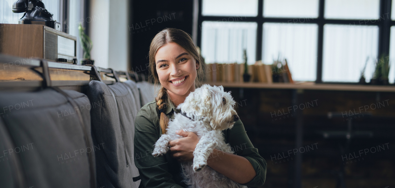 Portrait of beautiful young woman holding her dog and smiling. Cute white dog in arms of loving owner. With dog in coffe shop.