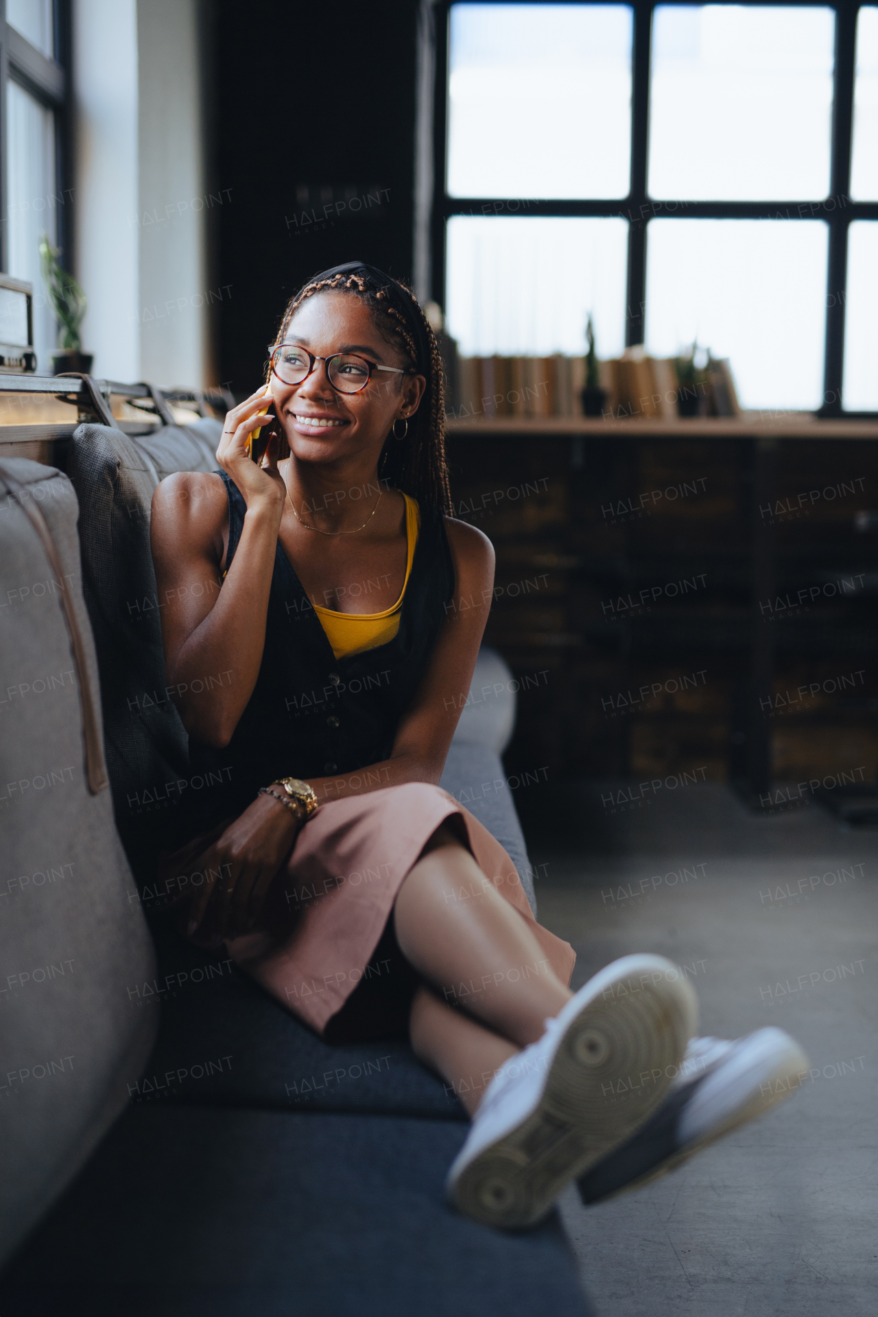 Portrait of beautiful woman sitting in modern office and making phone call, smiling. Working remotely from the coffee shop, relaxed atmosphere.