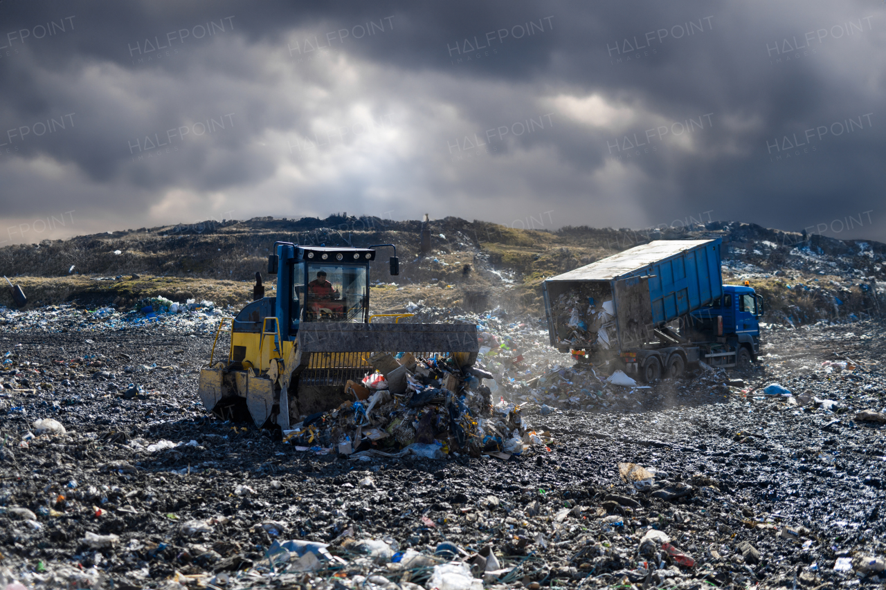 Garbage truck unloading waste on landfill, environmental concept. Copy space.