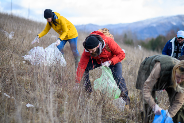 Group of activists picking up litter in the nature, environmental pollution, eco activism. and plogging concept.