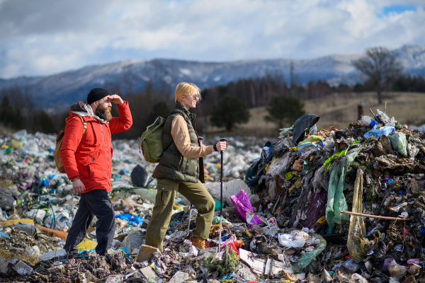 Man with gas mask holding potted plant on landfill standing on landfill, large pile of waste, environmental concept and eco activism.