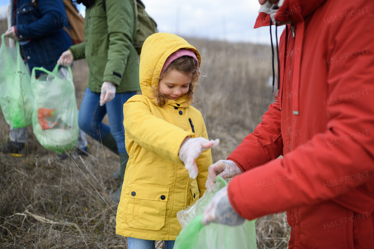 Young girl among eco activists picking up litter in nature, environmental pollution, eco activism and plogging concept.