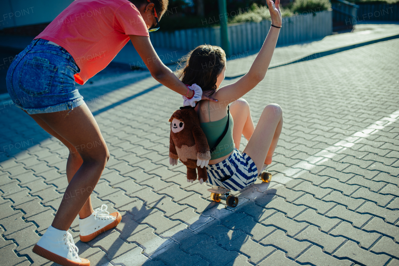 Young teenager girl best friends with skateboards spending time outdoors in city during warm summer holiday day. Riding skate, having fun.