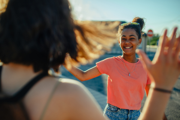 Young teenager girl best friends with skateboards spending time outdoors in city during warm summer holiday day.