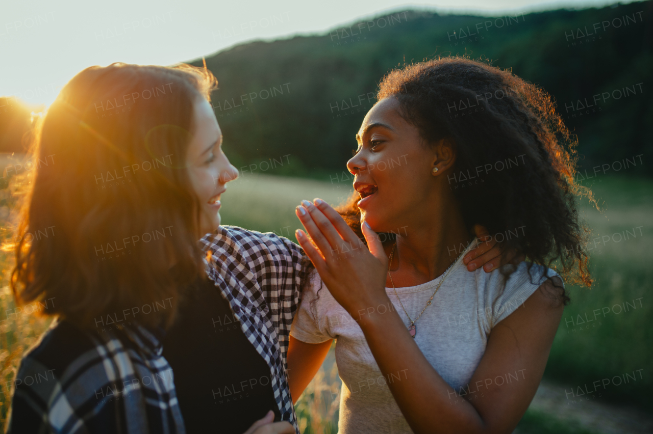 Cheerful young teenager girl best friends spending time in nature, during sunset. Girls on walk, embracing.