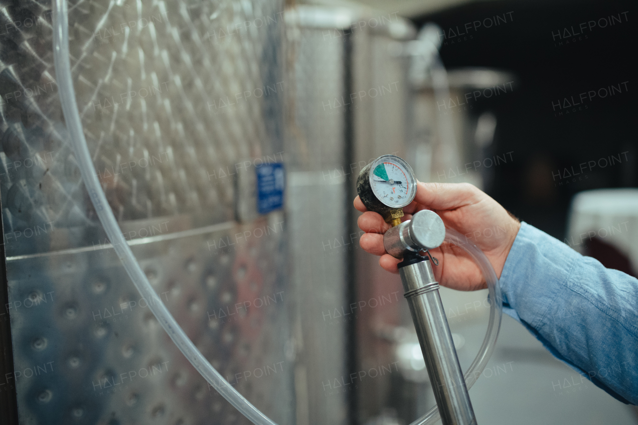 Winemaker standing in the wine cellar, controlling pressure in fermentation tank