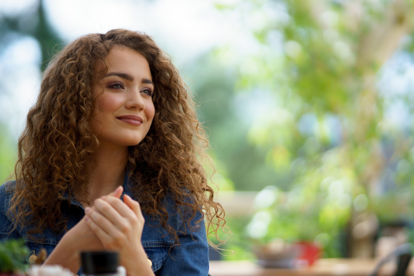 Beautiful woman sanitizing her hands with disinfectant gel in a restaurant before eating. Having lunch or brunch outdoors in restaurant patio.