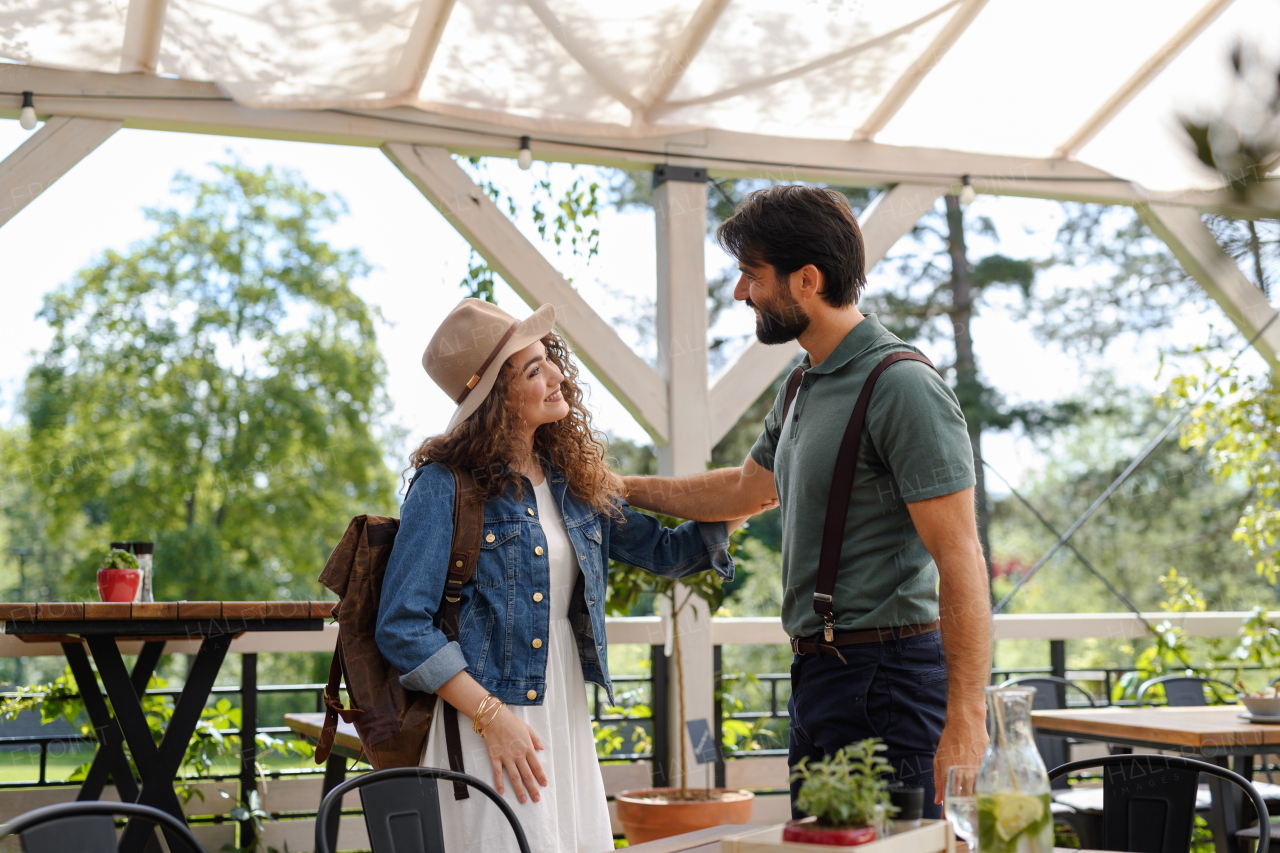 Friends meeting at a restaurant terrace. Greeting and hugging, after long time of not seeing each other. Concept of long-term friendships.