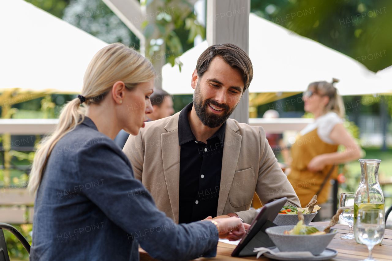 Business lunch for two managers, discussing new business project. Couple sitting outdoors on terrace restaurant, having romantic dinner date.