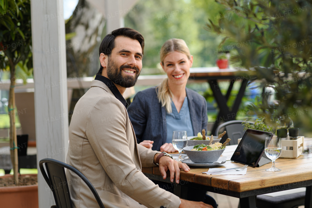 Business lunch for two managers, discussing new business project. Couple sitting outdoors on terrace restaurant, having romantic dinner date.