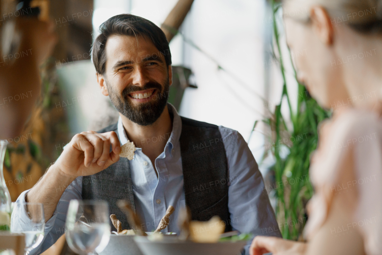 Happy loving couple at date in restaurant. Husband and wife sitting at table, laughing, having brunch, lunch in modern cafe.