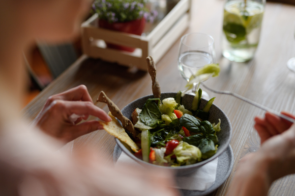 Close up of vegetable salad serving in restaurant, customer eating healthy food from china bowl.