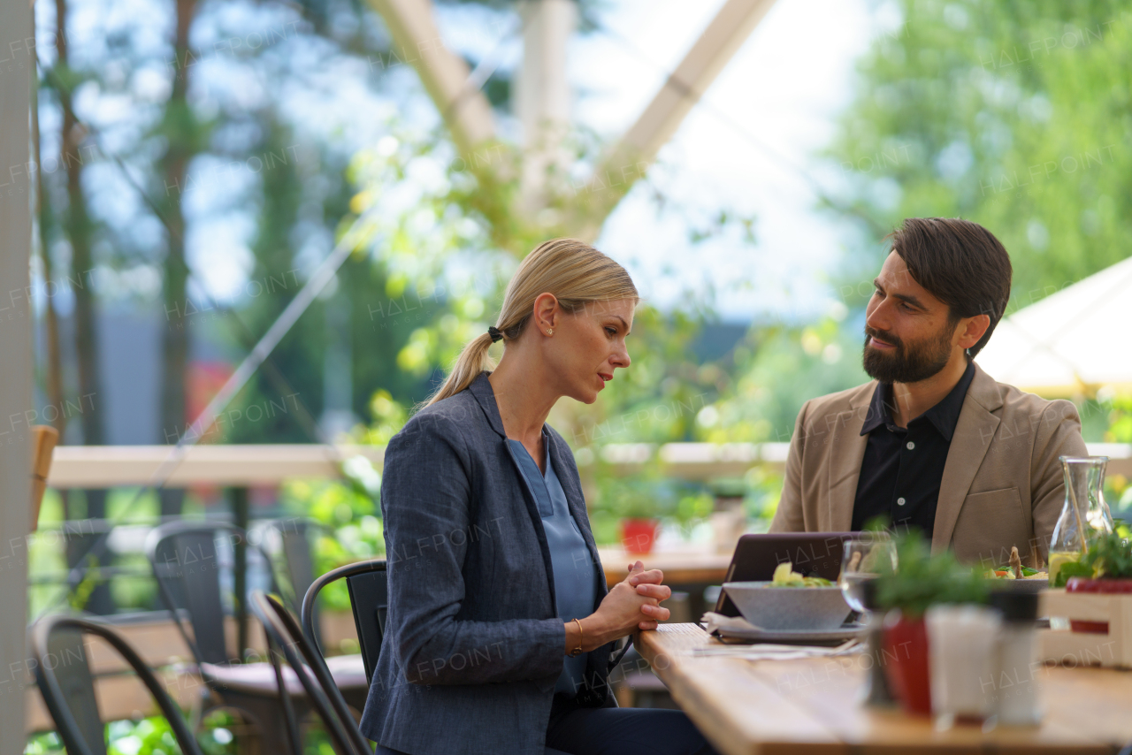 Business lunch for two managers, discussing new business project. Couple sitting outdoors on terrace restaurant, having romantic dinner date.