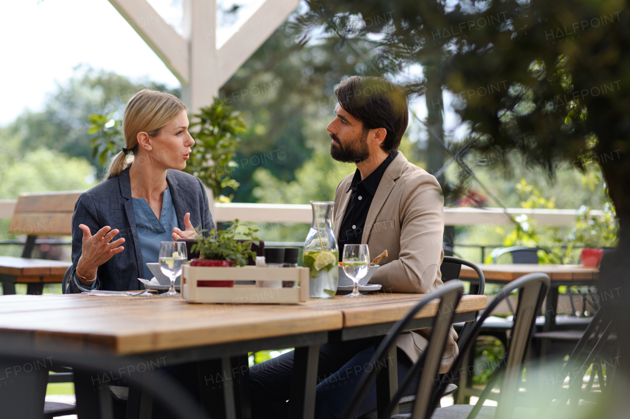 Business lunch for two managers, discussing new business project. Couple sitting outdoors on terrace restaurant, having romantic dinner date.