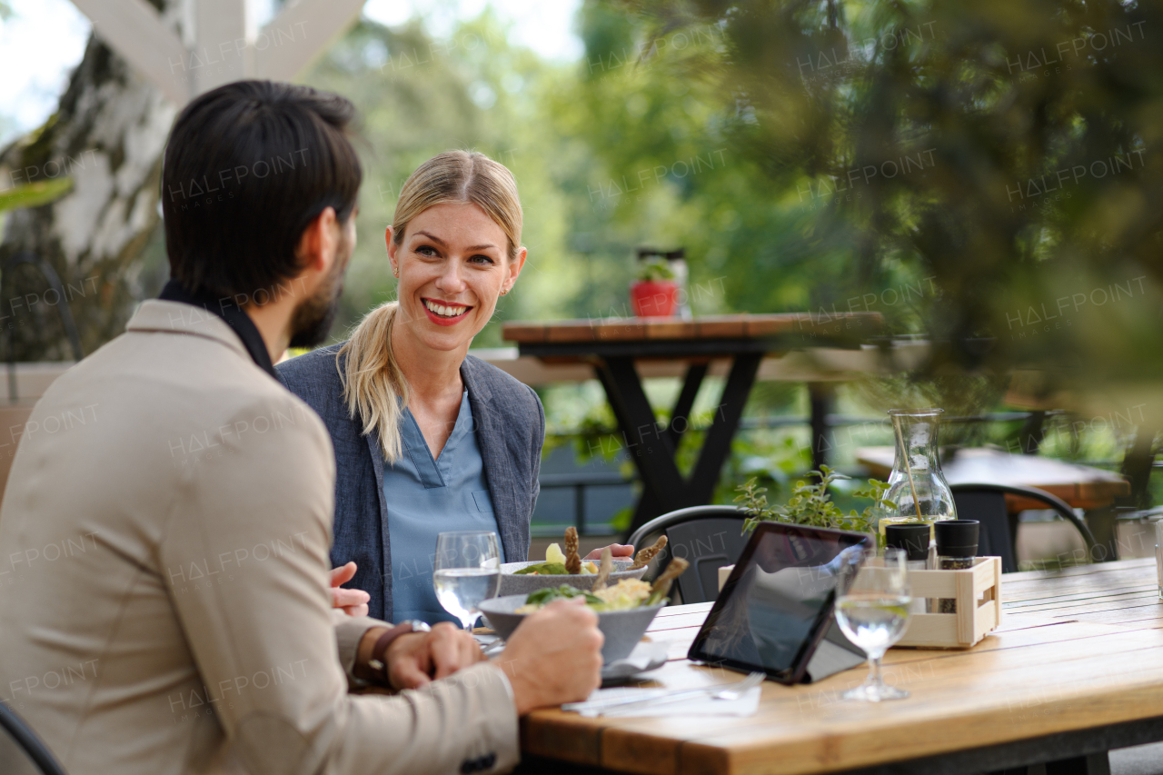 Business lunch for two managers, discussing new business project. Couple sitting outdoors on terrace restaurant, having romantic dinner date.