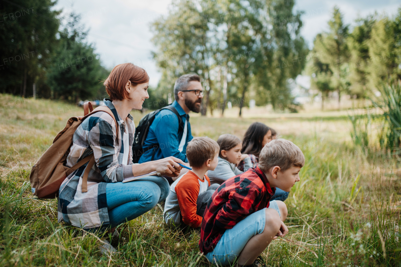 Teacher showing lake water to school children, during field teaching class. Outdoor active education helping young student to learn about ecosystem, nature.