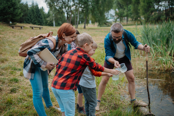 Teacher showing lake water to school children, during field teaching class. Outdoor active education helping young student to learn about ecosystem, nature.