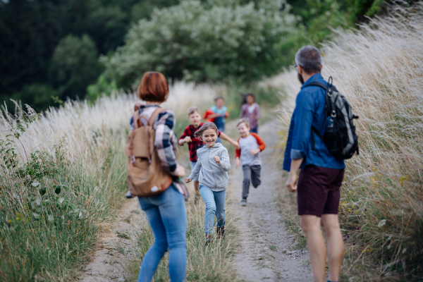 Young students having fun during biology field teaching class, running down the dirt path. Dedicated teachers during outdoor active education teaching about ecosystem, ecology and nature.