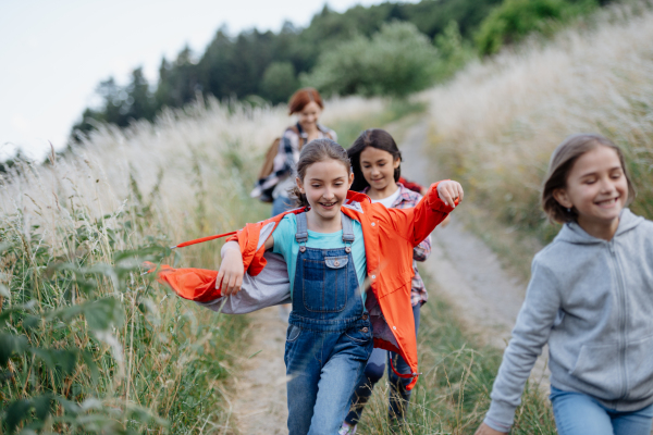 Young students having fun during biology field teaching class, running down the dirt path. Dedicated teachers during outdoor active education teaching about ecosystem, ecology and nature.