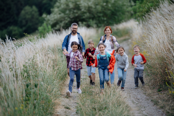 Young students having fun during biology field teaching class, running down the dirt path. Dedicated teachers during outdoor active education teaching about ecosystem, ecology and nature.