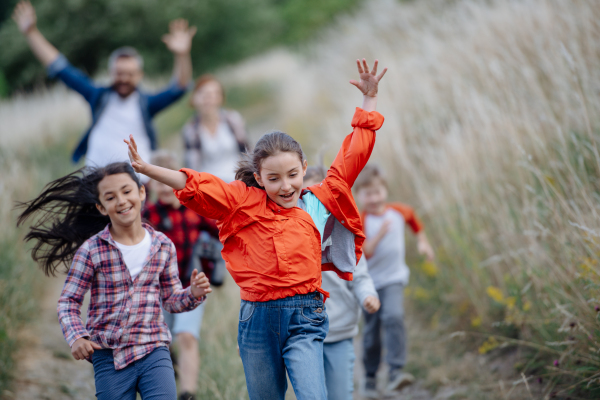 Young students having fun during biology field teaching class, running down the dirt path. Dedicated teachers during outdoor active education teaching about ecosystem, ecology and nature.