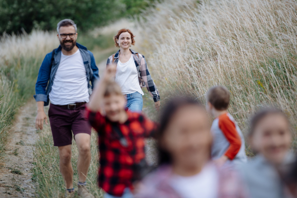 Young students having fun during biology field teaching class, running down the dirt path. Dedicated teachers during outdoor active education teaching about ecosystem, ecology and nature.