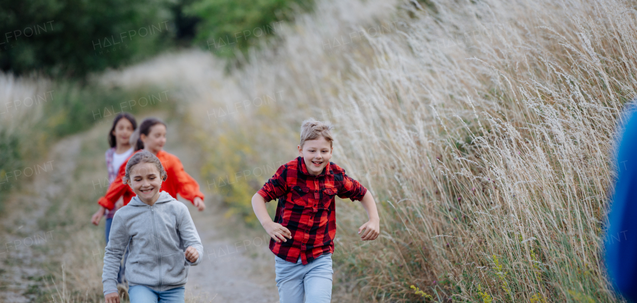 Young students having fun during biology field teaching class, running down the dirt path. Dedicated teachers during outdoor active education teaching about ecosystem, ecology and nature.