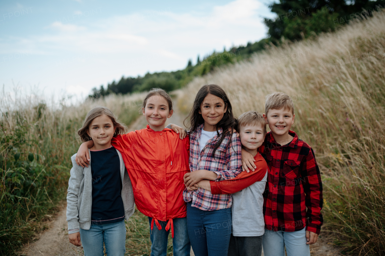 Portrait of young classmates, students during biology field teaching class, standing in the middle of meadow. Learning about ecosystem, ecology and nature.