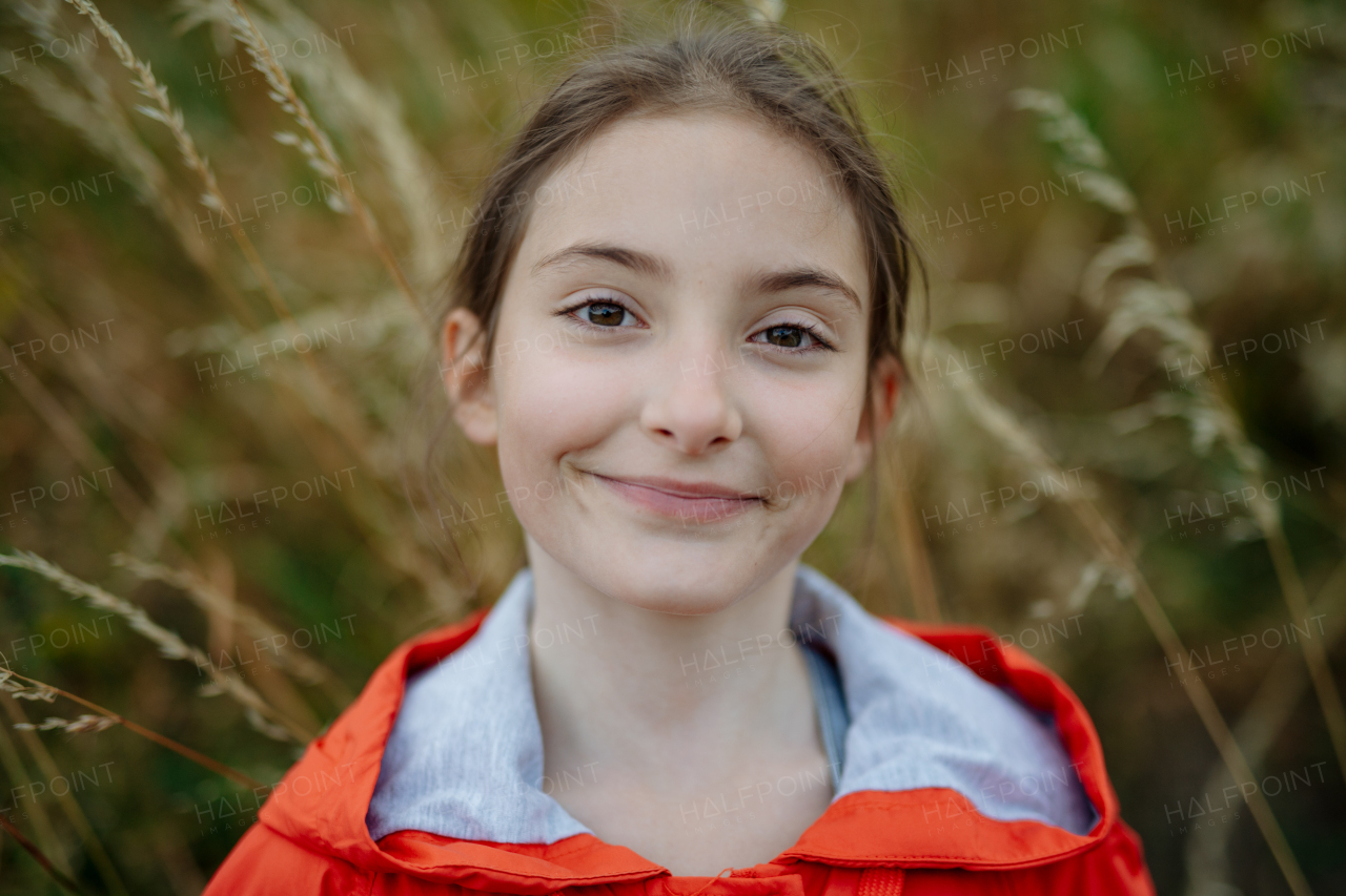 Portrait of beautiful young girl standing in nature, in the middle of tall grass with closed eyes, headshot. Copy space.