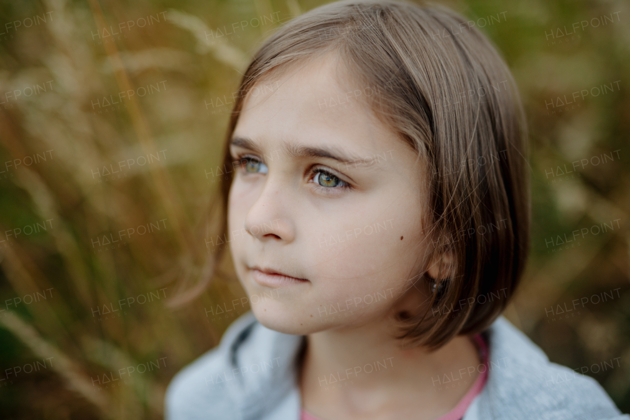 Portrait of beautiful young girl standing in nature, in the middle of tall grass with closed eyes, headshot. Copy space.